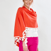 Woman in coral/white tassel ruana